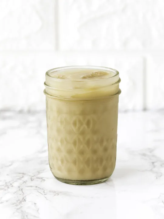 Iced coffee in a mason jar on white counter