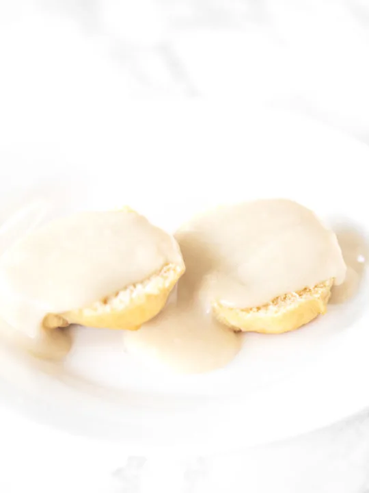 Biscuits and gravy without meat on a white plate on a white marble counter