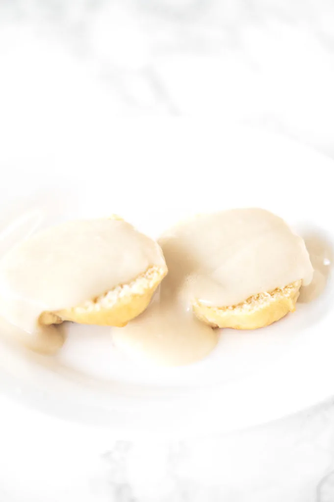 Biscuits and gravy without meat on a white plate on a white marble counter