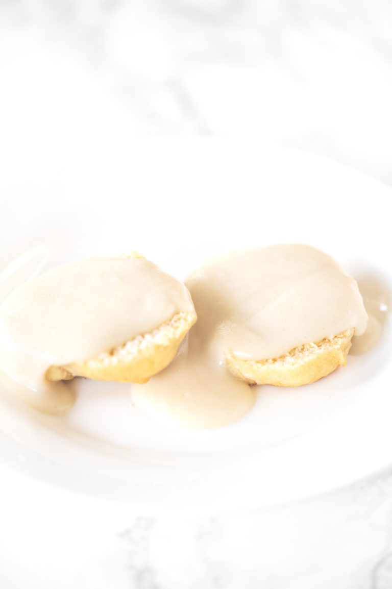 Biscuits and gravy without meat on a white plate on a white marble counter