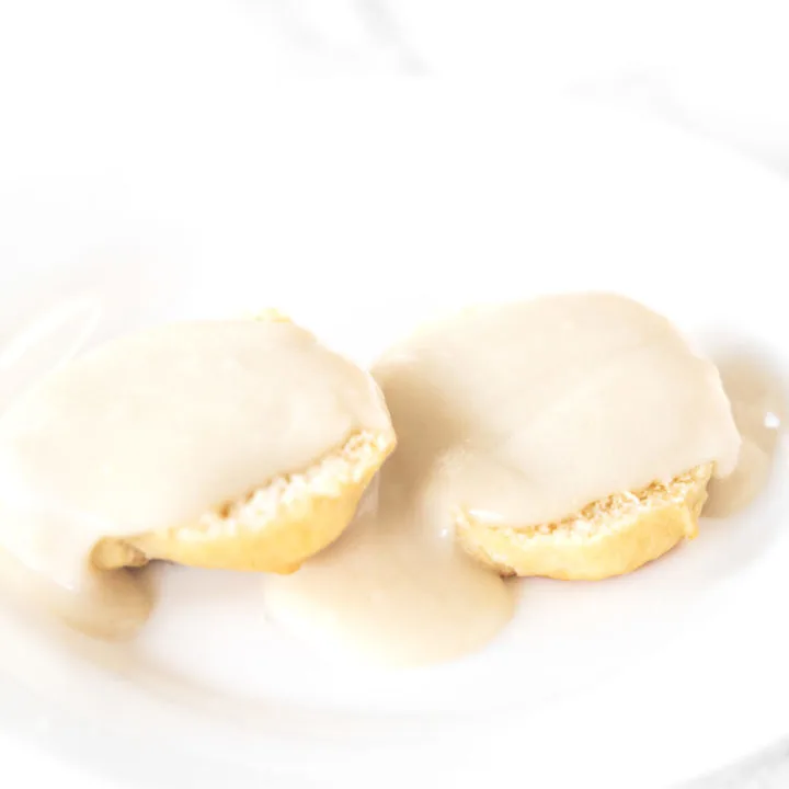 Biscuits and gravy without meat on a white plate on a white marble counter