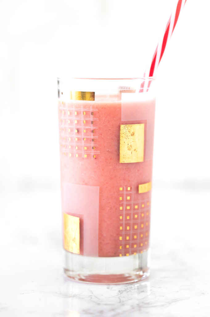 Dairy free strawberry smoothie in a glass with a red straw