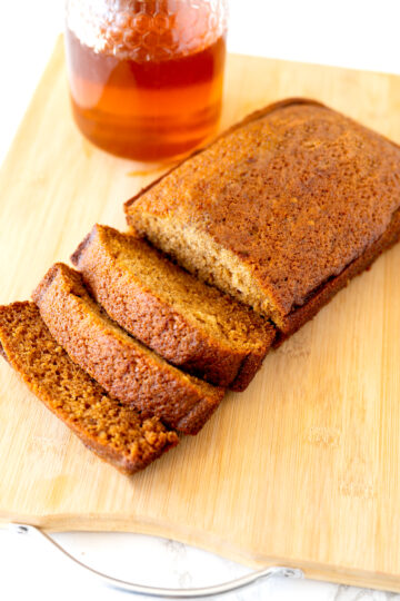 Jewish honey cake on a cutting board with honey in the background