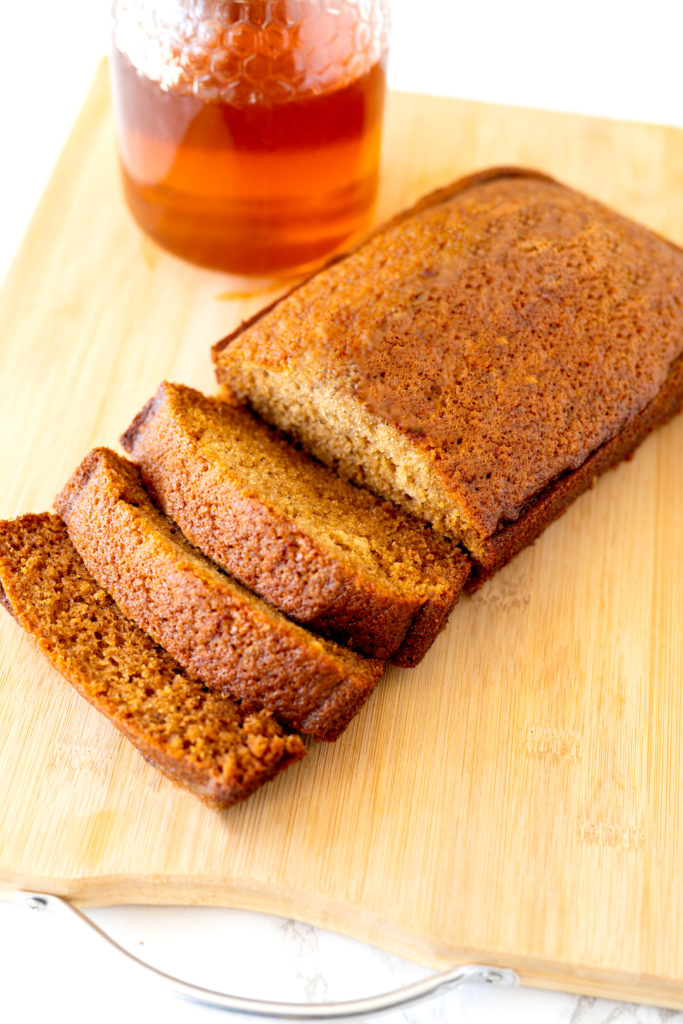 Jewish honey cake on a cutting board with honey in the background
