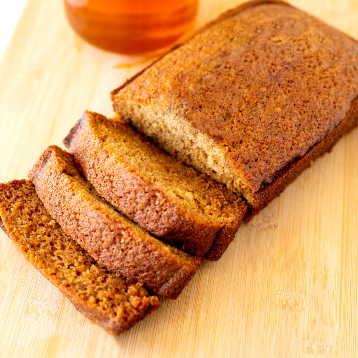 Jewish honey cake on a cutting board with honey in the background