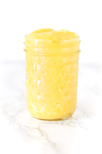 lemon curd in a jar on a white marble counter