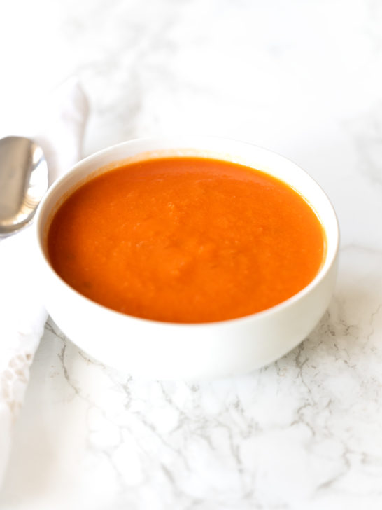 Dairy free tomato soup in a white bowl on a white marble counter