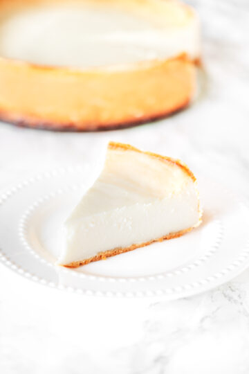 a slice of cheesecake with a cheesecake in the background