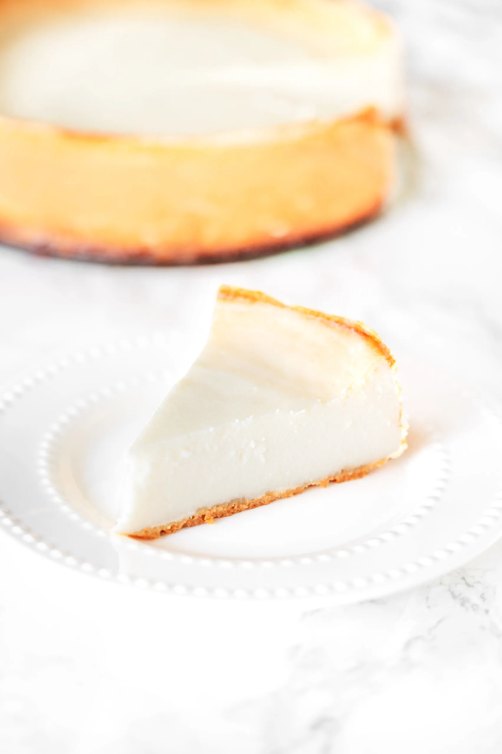 a slice of cheesecake with a cheesecake in the background