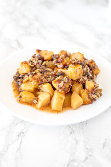 apple crisp on a white plate on a white marble counter