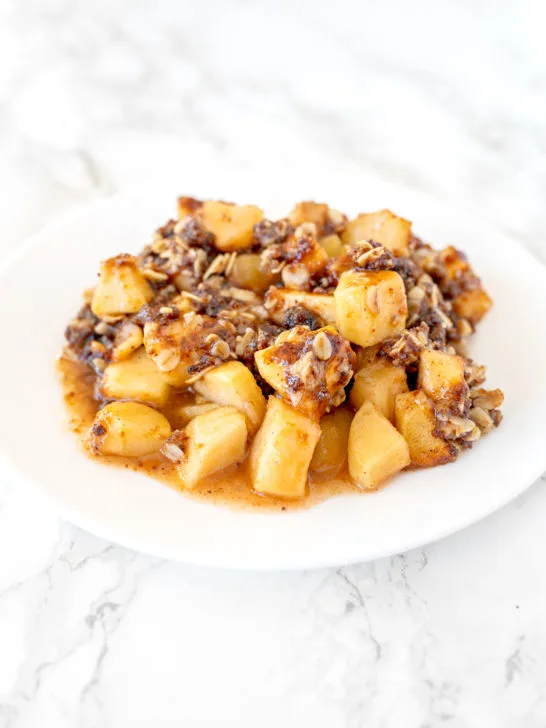 apple crisp on a white plate on a white marble counter