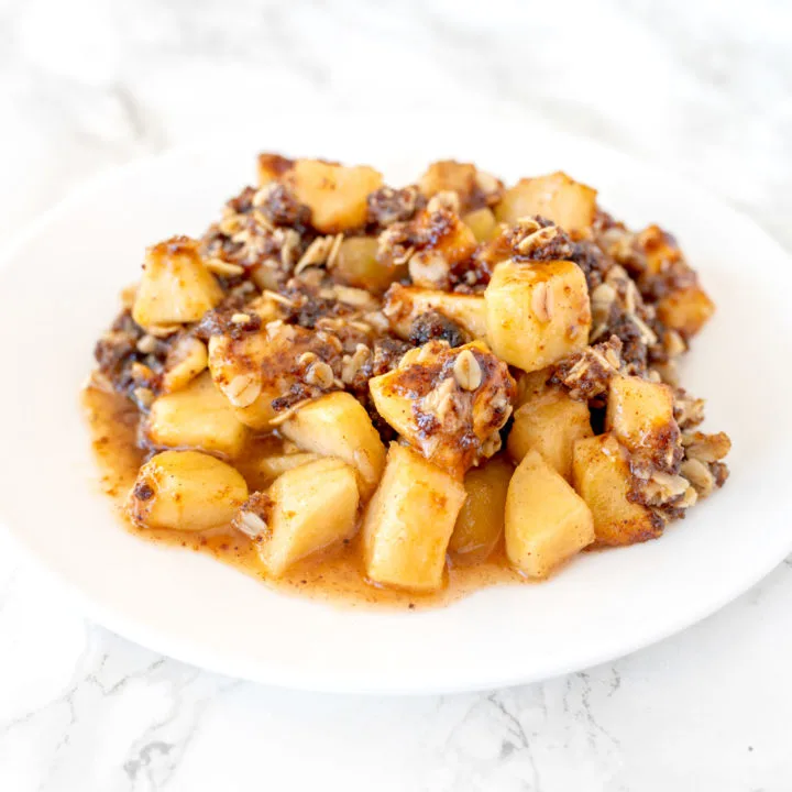 apple crisp on a white plate on a white marble counter