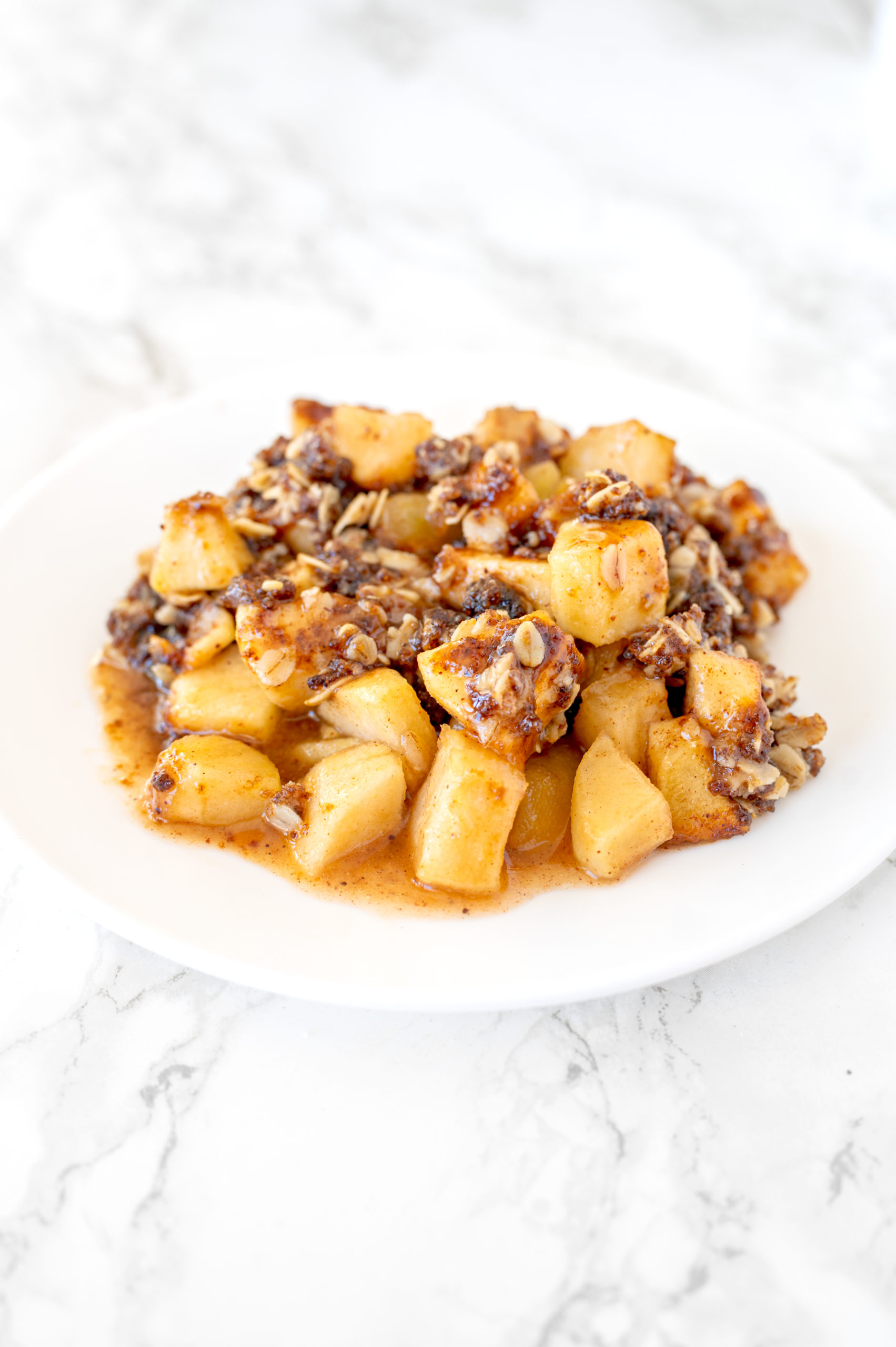apple crisp on a white plate on a white marble counter