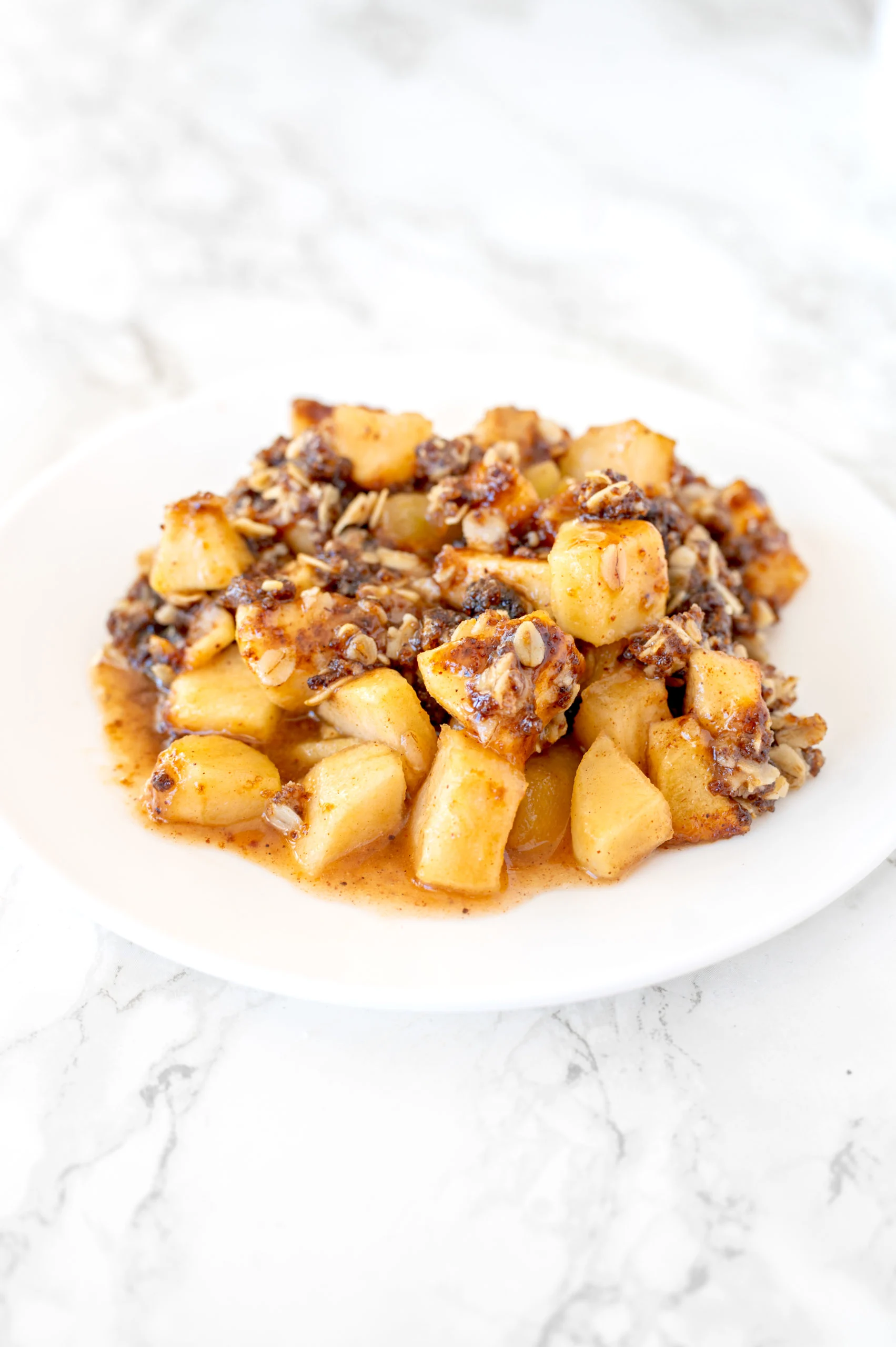 apple crisp on a white plate on a white marble counter
