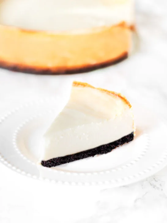 brownie bottom cheese cake on a plate on a white marble counter