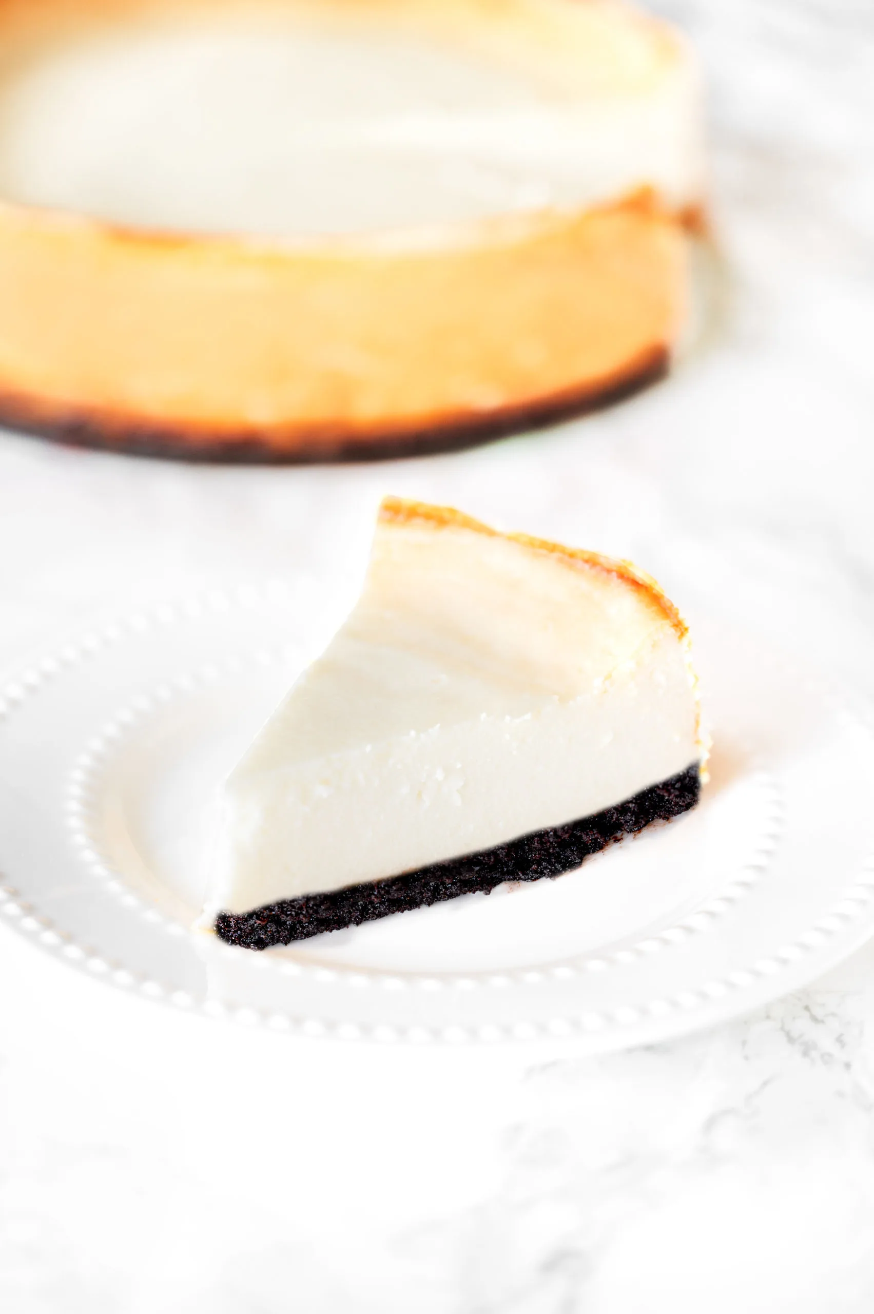 brownie bottom cheesecake on a plate on a white marble counter
