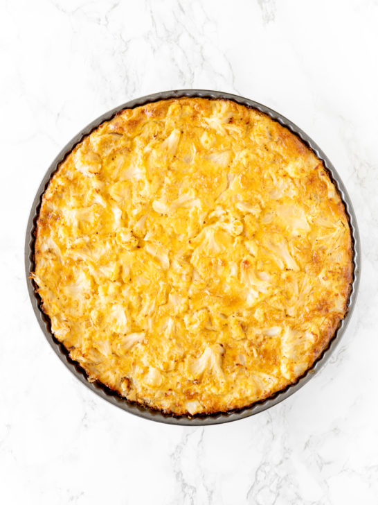 cauliflower kugel in a round pan on a white marble counter