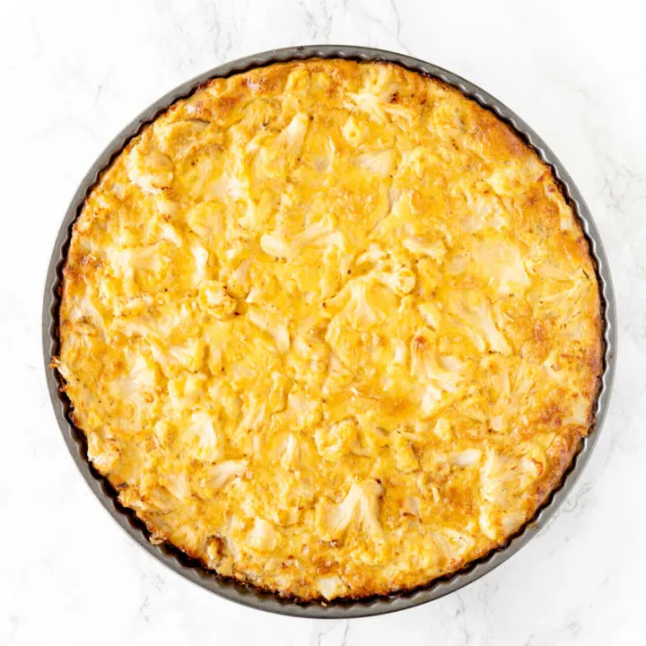 cauliflower kugel in a round pan on a white marble counter