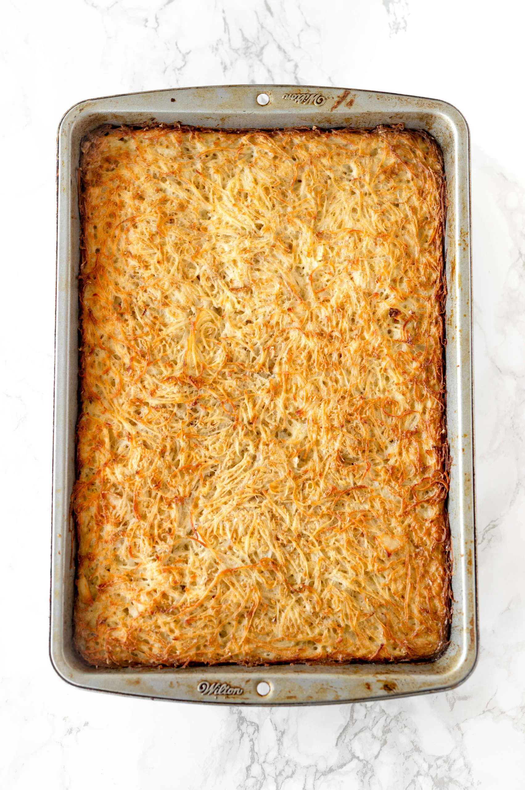 passover potato kugel in a baking pan on a white marble counter